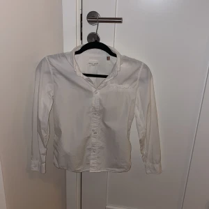 Vit skjorta från Holly & Whyte by Lindex - Säljer en stilren vit skjorta från Holly & Whyte by Lindex. Skjortan är i storlek 152 och har långa ärmar med knappar framtill. Perfekt för både vardag och festliga tillfällen. Den är i bra skick och redo för en ny ägare!