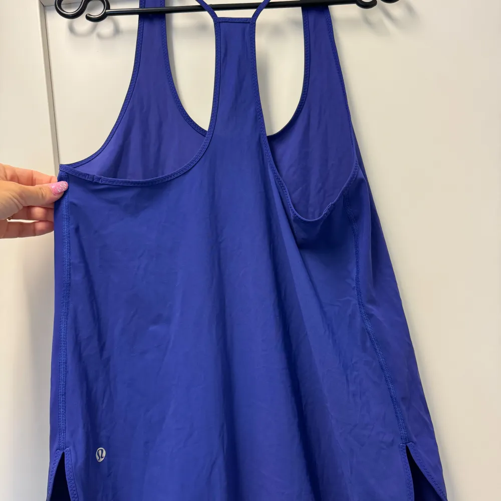 Säljer en snygg blå linnetopp från Lululemon. Perfekt för träning eller en varm sommardag. Toppen är ärmlös och har en stilren design med ett litet Lululemon-märke på sidan. Materialet känns lätt och bekvämt.. Sportswear.