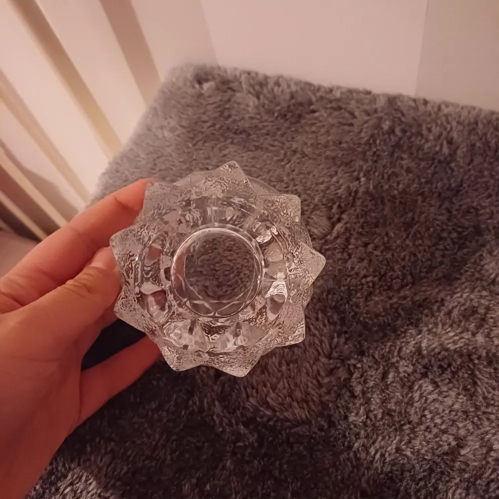 Säljer en superfin ljushållare i glas som ser ut som en kristallblomma. Den har en cool, geometrisk design med många facetter som reflekterar ljuset på ett magiskt sätt. Perfekt för att skapa mysig stämning hemma!. Accessoarer.