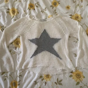 Vit stickad tröja med stjärna från Selected Touch - Säljer en vit stickad tröja från Selected Touch med en stor grå stjärna på framsidan. Tröjan har långa ärmar och en avslappnad passform. Perfekt för en mysig dag hemma eller en avslappnad utflykt.