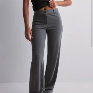 Grå kostymbyxor från Nelly - Snygga grå kostymbyxor från nelly med medelhög/högmidja och raka ben. Världens skönaste material o sitter verkligen som smäcken🥰