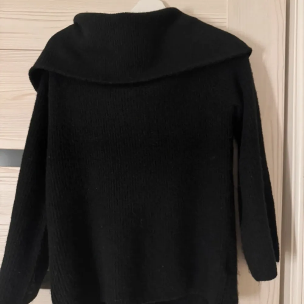 Säljer en stilren svart offshoulder tröja med långa ärmar. Perfekt för en avslappnad och trendig look. Tröjan har en lös passform och är tillverkad i ett mjukt material som känns skönt mot huden.. Neuletakit & Villapaidat.