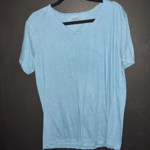 Ljusblå t-shirt med v-ringning - Säljer en ljusblå t-shirt med v-ringning från T-Shirt One Basic. Perfekt för en avslappnad stil. 