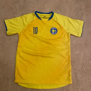 Gul Sverige fotbollströja från H&M 146/152 - Snygg gul Sverige ströja från H&M med blå detaljer. Tröjan har korta ärmar och nummer 10 tryckt på ryggen tillsammans med texten Sverige på ryggen Perfekt för unga fotbollsfans.