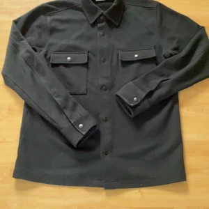 Svart overshirt från Selected Homme - Snygg svart overshirt från Selected Homme med knappar framtill och två bröstfickor med lock. Perfekt för lager-på-lager-stil och passar till många olika outfits. Nypris 799kr Skitsnygg Knappast använd 9/10 skick. skicka prisförslag!!!