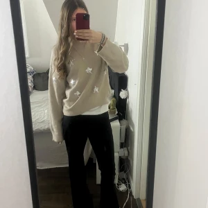 Beige stickad tröja med stjärnor från Gina Tricot - Säljer en beige stickad tröja från Gina Tricot med glittriga stjärnor. Tröjan har långa ärmar och en bekväm passform. super fin och bra skick, säljer då den aldrig kommer till användning💗