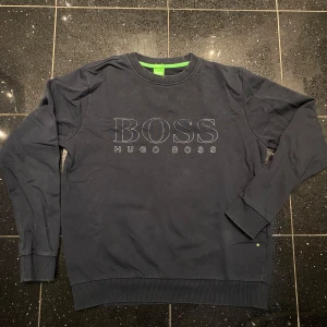 Hugo boss tröja  - Hugo boss tröja, storlek S herrmodell. Mörkblå, bra skick. Ett litet hål i ena armhålan, men syns inte mycket när man har på sig den. 