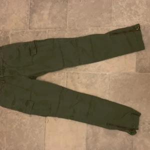 Gröna cargobyxor från L.O.G.G. - Snygga gröna cargobyxor från L.O.G.G. med flera praktiska fickor. Byxorna har en tight passform och är perfekta för en avslappnad stil. Tillverkade i ett slitstarkt material som passar bra för utomhusaktiviteter.