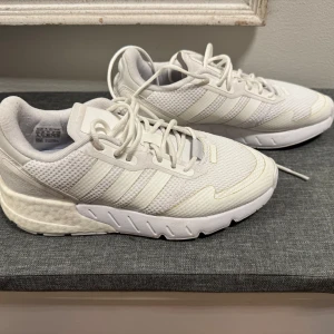 Vita sneakers från Adidas - Säljer dessa då jag ej använder dem! Använda ca 5gånger . Snygga vita sneakers från Adidas med klassiska tre ränder på sidan. Skorna har en bekväm sula och snörning framtill. Perfekta för en stilren look.