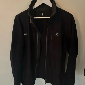 Svart Haglöfs jacka - Säljer en svart jacka från Haglöfs med dragkedja framtill. Jackan har en stilren design och är perfekt för utomhusaktiviteter. Jackan är i nyskick och har väldigt skönt material.