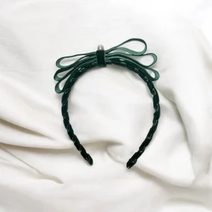 Grönt diadem med rosett och pärla - Elegant grönt diadem i sammet med en dekorativ rosett och en pärla på toppen. Perfekt för att ge en stilfull touch till din outfit.