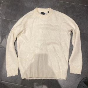 Beige tröja från Paul Hunter - Säljer en stilren beige tröja från Paul Hunter i lammullsmix. Tröjan har en klassisk rund hals och ribbade muddar vid ärmslut och nederkant. Perfekt för kyligare dagar.