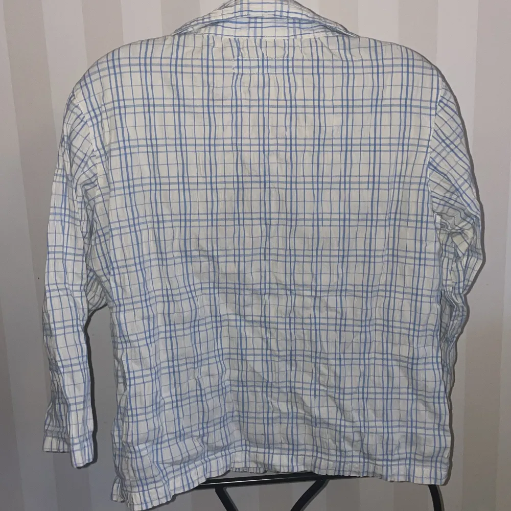 Säljer en vit och blå rutig skjorta från Drop med broderade blommor i blått på framsidan st158-164. Skjortan har långa ärmar och knappar framtill. Perfekt för en avslappnad stil med en touch av detaljer.. Paidat.