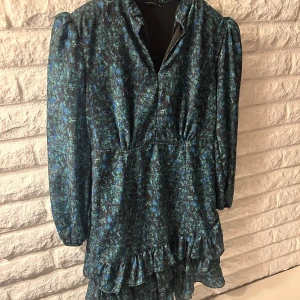 Blommig klänning från Trendyol - Snygg blommig klänning från Trendyol i blå och svarta toner. Klänningen har långa ärmar och volangdetaljer vid fållen. Perfekt för en stilfull look. Pris kan diskuteras.