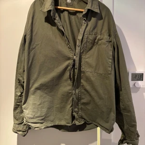 Grön overshirt från C.P. Company - Säljer en grön overshirt från C.P. Company med långa ärmar och knappdetaljer. Säljer p.g.a vuxit ur den.