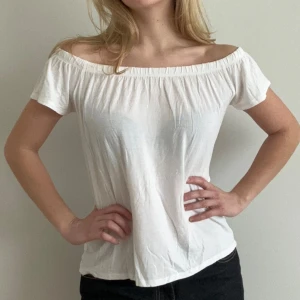 Vit offshoulder topp - Säljer en stilren vit offshoulder topp med korta ärmar. Perfekt för varma dagar och ger en avslappnad look. Toppen är tillverkad i ett mjukt och bekvämt material.