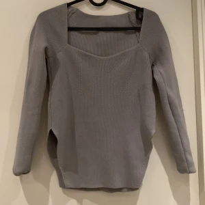 Grå ribbad tröja - Säljer en stilren grå ribbad tröja med fyrkantig halsringning. Tröjan har långa ärmar och en figurnära passform som ger en elegant look. Perfekt för kyligare dagar.