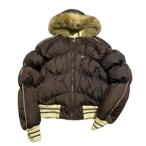 2000s brun /guld pufferjacka med pälskrage🤎 - Helt ny, oanvänd. Inga defekter alls. Snyggaste brun/guld pufferjacka som är tvåsidig. Jackan har en fluffig pälskantad huva och dragkedja framtill. Den är perfekt för vinter. Den har många fina guldiga detaljer. Perfekt för kyliga dagar! Storlek L, passar även M/L. Skriv vid frågor❕