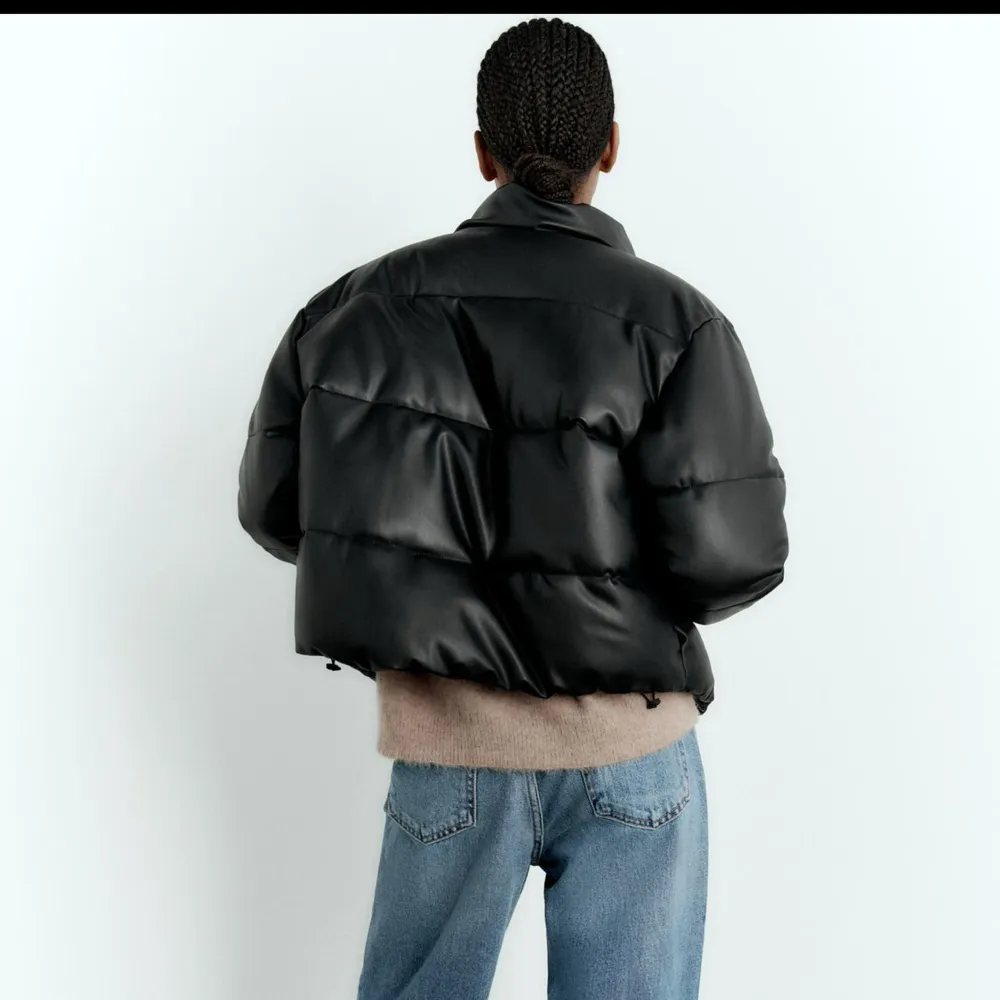 Snygg svart pufferjacka med hög krage och dragkedja framtill. Jackan har en croppad design och är perfekt för kyligare dagar.. Takit.
