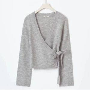 Grå omlottkofta med knyt från Gina tricot - Mysig grå omlottkofta med knyt i sidan. Perfekt för lager-på-lager och har långa ärmar. En stilren och bekväm tröja för kyligare dagar. Endast testad! pris kan diskuteras vid snabb affär