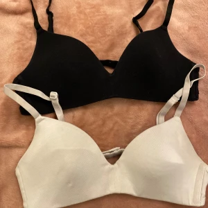 Svart och vit bh samt vit sport-bh - Två bh:ar i svart och vit med justerbara axelband och en vit sport-bh utan byglar. Perfekt för både vardag och träning.