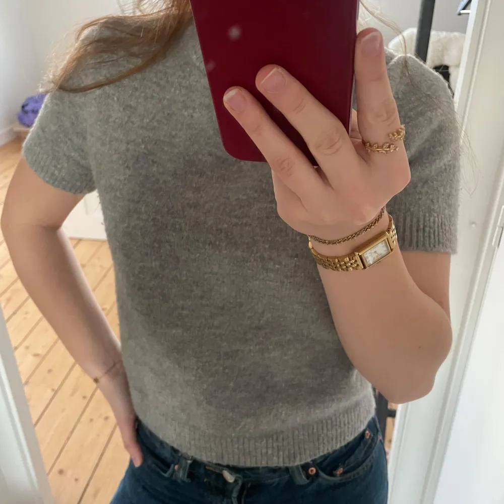 Säljer en stilren grå stickad tröja med korta ärmar. Perfekt för en avslappnad look. Tröjan har en rund halsringning och ribbade kanter.❣️❣️. Neuletakit & Villapaidat.