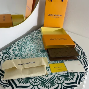 Lång Plånbok från - Hej! Jag Säljer nu en ny samt oanvänd snygg elegant brun lång plånbok med klassiskt monogrammönster. Plånboken har flera kortfack och en dragkedjeficka för mynt. Perfekt för att hålla ordning på dina kort och kontanter. Alla tillbehör som finns med på bilderna medföljer självklart. Priset kan diskuteras vid snabb affär. Kan både frakta och mötas 