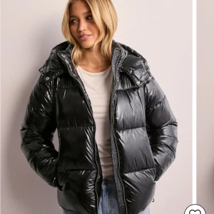 Svart glansig pufferjacka med huva - Snygg svart pufferjacka med glansig finish och praktisk huva. Original priset är 800kr men jag säljer den för 650kr. Storleken är i xxs men jag skulle säga att den passar Xs också.
