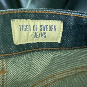 Mörkblå jeans från Tiger of Sweden - Snygga mörkblå jeans från Tiger of Sweden med klassisk femficksdesign. Jeansen har en rak passform och är tillverkade i högkvalitativt denim. Perfekta för en stilren look. Modellen heter Rex och storleken är 31/32