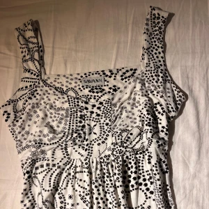 Vit och svart mönstrad klänning från Savann - Säljer en vit klänning med svart mönster. Aldrig använt. 