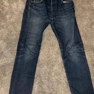Blå jeans från Levi's - Säljer ett par klassiska blå Levi's 501 jeans. De har en straight passform och är tillverkade i slitstarkt denim. Perfekta för en avslappnad stil med knappgylf och fem fickor.