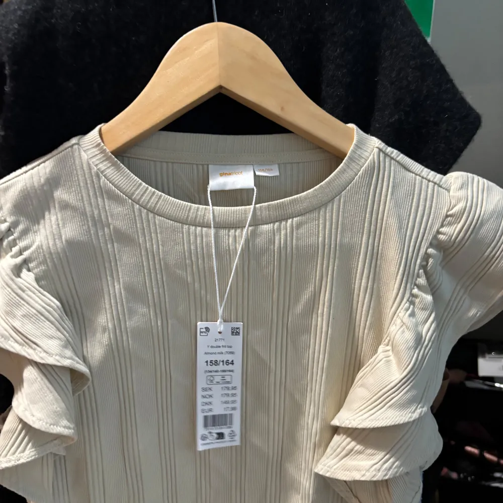 Säljer en stilren beige ribbad topp från Gina Tricot med volangdetaljer på ärmarna. Perfekt för en trendig look. 🧡. Yläosat.