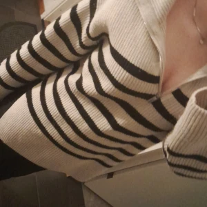 Randig stickad tröja från H&M - Säljer en mysig randig tröja från H&M i krämvit och svart. Tröjan är stickad med långa ärmar och har en bekväm passform. Perfekt för kyligare dagar nu under vintern! 