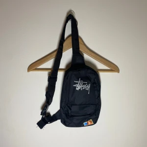 Stussy axelväska - 	•	Stussy axelväska 	•	Justerbar axelrem för bekväm användning 	•	Kompakt och praktisk design 	•	En huvudficka och en mindre ficka för förvaring 	•	I bra skick!