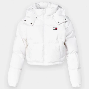 Vit pufferjacka från Tommy hilfigher  - Säljer en snygg vit pufferjacka från Tommy hilfigher, modell 'The Alaska Puffer'. Jackan har en huva och dragkedja framtill. Jackan har några tecken på användning, två synligare fläckar inuti och en väldigt svag framtill (se första bilden) därav det billiga priset! Köpt på Zalando.