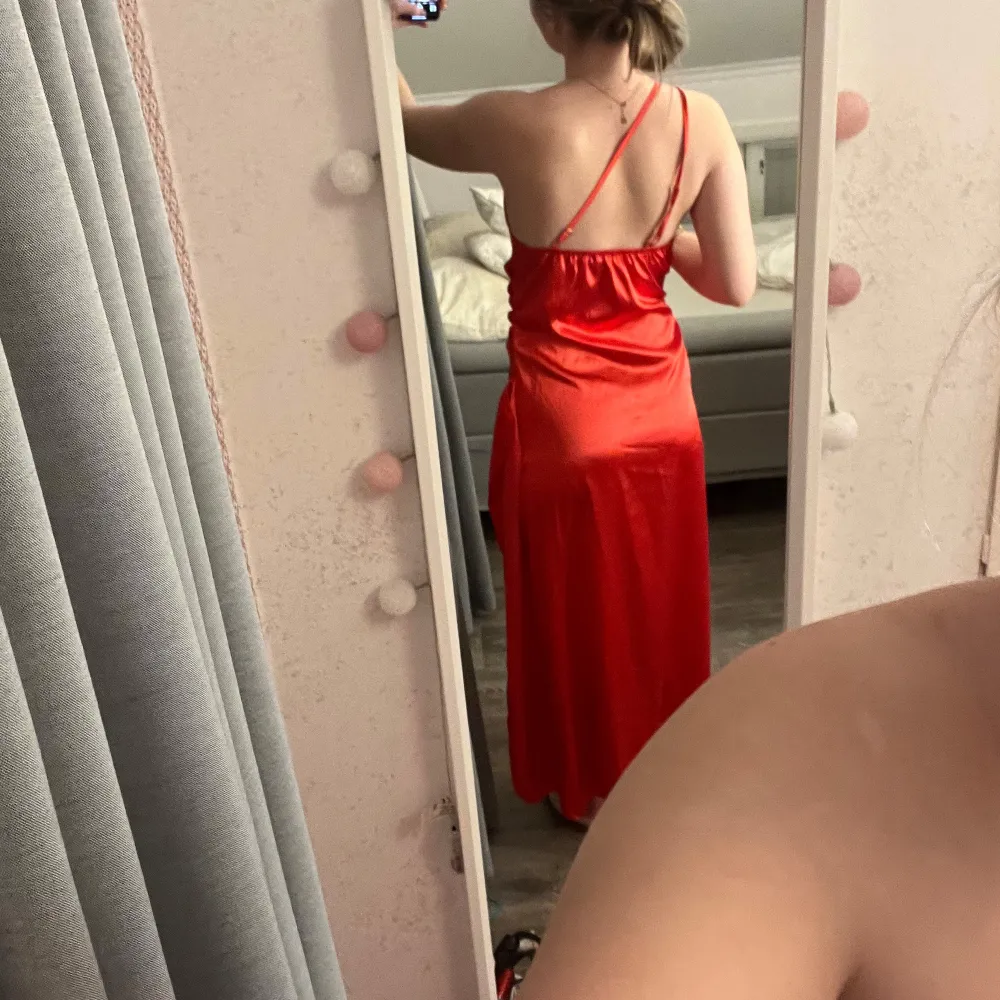 Snygg röd oneshoulder klänning med slits och dragkedja. Satintyg och blänkande röd/orange/rosa färg, perfekt till tex bal! Oanvänd då den är för kort för mig som är ca 165💕. Mekot.