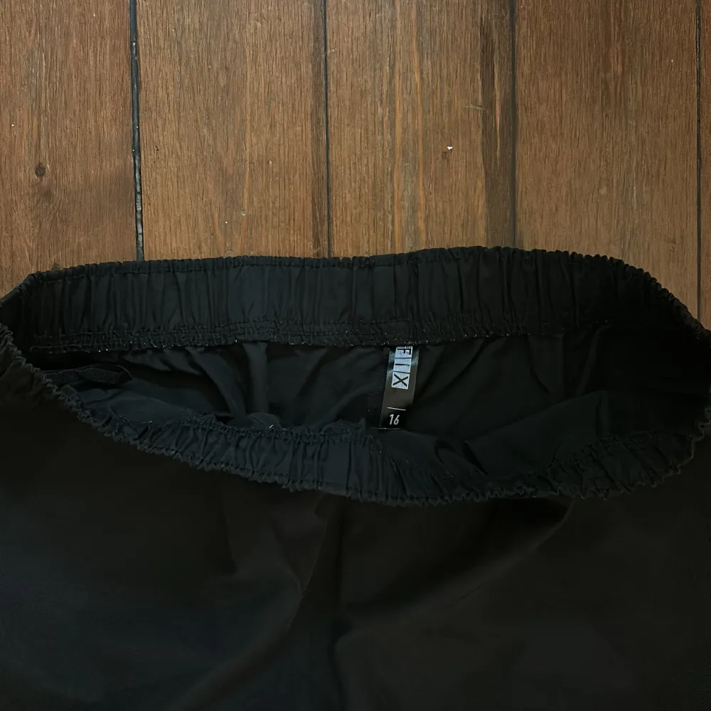 Snygga svarta byxor med resårmidja och justerbara benslut. Perfekta för en avslappnad stil. Byxorna har en loose passform och är tillverkade i ett lätt material.. Farkut & Housut.