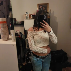 Vit spetsblus - Säljer en söt vit spetsblus med offshoulder-design och långa ärmar. Perfekt för en stilren och romantisk look. Blusen är croppad och passar utmärkt till både jeans och kjol.