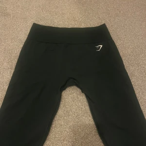 Mörkgrön leggings från Gymshark - Snygga svarta leggings från Gymshark med hög midja och en diskret logga på sidan. Perfekta för träning med en tight passform som ger bra stöd. Materialet är stretchigt och bekvämt.