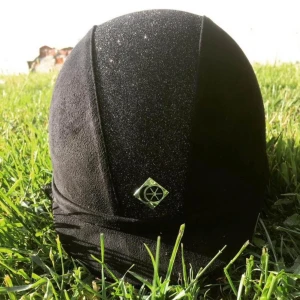 Svart hjälm från Charles & Owen - Elegant svart hjälm från Charles & Owen med glittrig detalj på ovansidan. Perfekt för ridning och har en stilren design med en liten logotyp framtill. Passar bra för den stilmedvetna ryttaren.