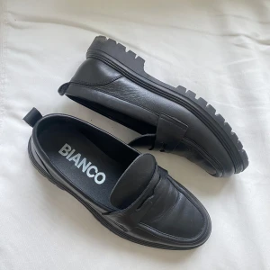 Svarta loafers Bianco - Snygga svarta loafers från Bianco i skinn med robust sula. Perfekta för en stilren look. Tillverkade i Portugal. Passar 45/46. Använda 1 gång