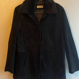 Svart mockajacka från SURE - Snygg svart mockajacka från SURE med quiltat foder och knäppning framtill. Jackan har en klassisk krage och långa ärmar, perfekt för kyligare dagar.