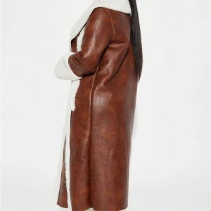 Brun lång kappa med vit fuskpäls - brun lång kappa med vit fuskpäls på krage och ärmslut  och varma material.  Säljer den på grund av att jag använder inte den.