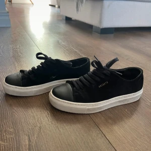 Svarta sneakers från Axel Arigato - Snygga svarta sneakers från Axel Arigato med vit sula och svarta snören. Skorna har en stilren design med en diskret logga på sidan. Storlek 35