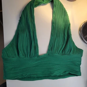 Grön halterneck topp från Shein - Snygg grön halterneck topp från Shein med ribbad textur. Perfekt för sommarens varma dagar. Toppen har en djup urringning och bred midjeband för en bekväm passform.