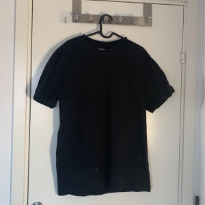 Svart t-shirt från 157 Roots - Snygg svart t-shirt från 157 Roots med en praktisk bröstficka. Perfekt för en avslappnad stil. Tillverkad i mjukt material för extra komfort.