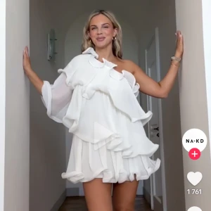 Vit volangklänning från NA-KD (SÖKER) - Söker den här klänningen från nakd, om det är någon som har den så är jag intresserad av att köpa🤍funkar i storlek 34 eller 36.