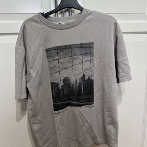 Beige t-shirt med stadsmotiv från Denim Day - Snygg beige t-shirt från Denim Day med ett coolt svartvitt stadsmotiv på framsidan. Perfekt för en avslappnad stil. Kortärmad och i en mjuk bomullskvalitet.