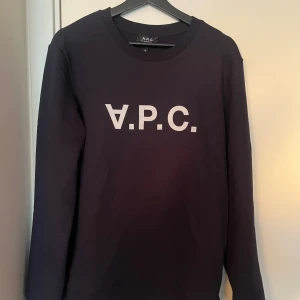 Mörkblå sweatshirt från A.P.C. - Säljer en stilren mörkblå sweatshirt från A.P.C. med vit logotyp på bröstet. Tröjan är helt NY!!! Tröjan har långa ärmar och en klassisk rund halsringning. Perfekt för en avslappnad look. Hör av dig vid fråga.