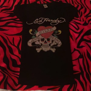Svart Ed Hardy t-shirt - Söt tröja från ed Hardy med rhinestones och tryck❤️tyvärr har stenarna trillat av förutom några, men den är ändå snygg och användbar!! Tar även byten mot en annan ed Hardy tröja!